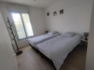 2 bedden in een witte kamer met een raam bij Bord de Seine in Carrières-sous-Poissy