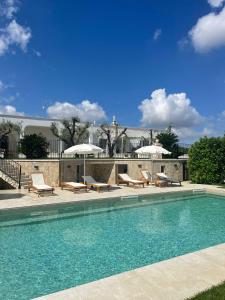 a swimming pool with chairs and umbrellas on a patio at Dimorae Camà in Cisternino