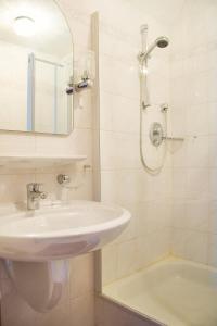 a bathroom with a sink and a mirror and a tub at Kurhotel Kaiser in Bad Wörishofen