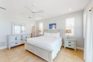 a white bedroom with a white bed and two night stands at A Sea Of Sand & Stars in St. George Island