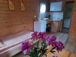 um quarto com uma cama e uma cozinha com flores roxas em Pod Bocianim Gniazdem 691-363-701 em Bachlowa