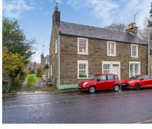 two red cars parked in front of a brick house at Pretty Ground Cottage in Comrie in Comrie