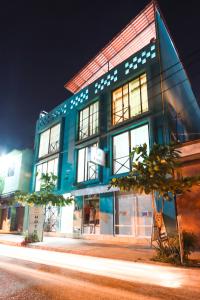 un bâtiment bleu avec des fenêtres donnant sur une rue la nuit dans l'établissement Hotel Guivá Huatulco, à Santa Cruz Huatulco