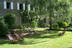 Deux chaises en bois assises dans l'herbe devant un bâtiment dans l'établissement Salomony Chambre d'Hôtes, à Marcols-les-Eaux
