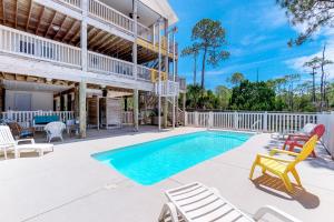 a swimming pool with chairs and a house at Footprints In The Sand in St. George Island