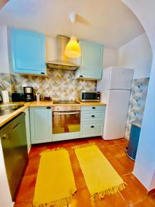 a kitchen with blue cabinets and yellow rugs at Golden Wave Surf Villa in Corralejo