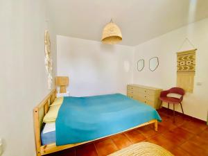 a bedroom with a blue bed and a chair at Golden Wave Surf Villa in Corralejo
