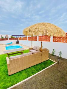 a patio with a table and a straw umbrella at Golden Wave Surf Villa in Corralejo