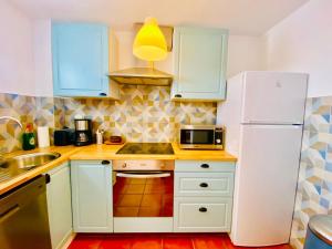 a kitchen with white cabinets and a white refrigerator at Golden Wave Surf Villa in Corralejo