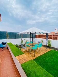 a patio with a table and chairs under an umbrella at Golden Wave Surf Villa in Corralejo