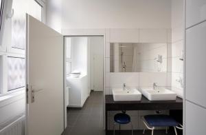 a white bathroom with two sinks and a mirror at Hüttenpalast in Berlin