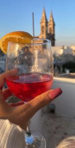 eine Hand, die ein Weinglas mit einer orangefarbenen Scheibe hält in der Unterkunft Jarubed in Alberobello