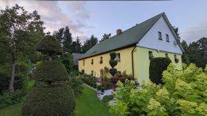 una grande casa gialla con un giardino di fronte di Przy Strumyku - Apartament w Górach Izerskich a Kłopotnica