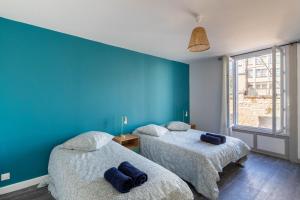 Maison de ville en plein centre avec terrasse في بواتييه: سريرين في غرفة بجدران زرقاء