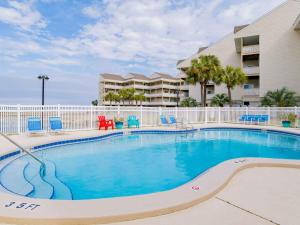 a swimming pool with blue chairs and a building at Baywatch #C5 in Pensacola Beach +19 photos