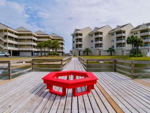 a red bench sitting on a deck in front of some apartment buildings at Baywatch #C5 in Pensacola Beach