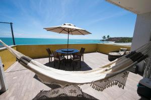 a hammock with a table and chairs and an umbrella at Cobertura e Flat Tabatinga in Conde