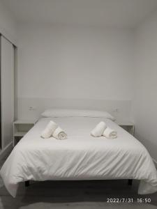 Una cama blanca con dos almohadas encima. en GRUPOELE3 MUXIA PUERTO en Muxia