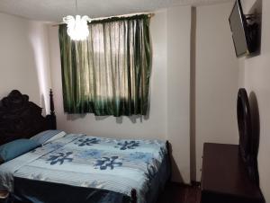 a bedroom with a bed with a blue comforter and a window at HOTEL SARAGURO LOJA in Loja