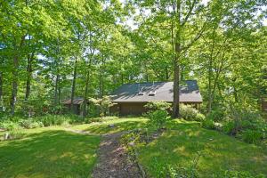 a house in the woods with a path leading to it at Little Brown House in Glen Arbor