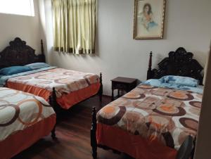 1 dormitorio con 2 camas y una foto en la pared en HOTEL SARAGURO LOJA en Loja