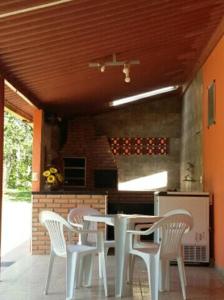 a kitchen with a white table and white chairs at Pousada e Restaurante Maria das Flores in Três Marias