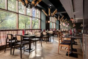 comedor con mesas y sillas y ventanas grandes en Scandic Helsinki Hub, en Helsinki