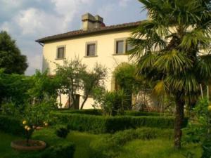 una grande casa bianca con una palma di fronte di Villa storica di Majano a Bagno a Ripoli