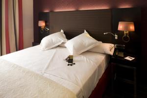 1 cama grande con sábanas y almohadas blancas y 2 lámparas en Hotel Boutique Gareus, en Valladolid