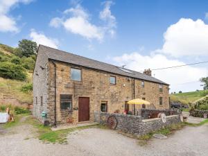 ein Steinhaus mit einem Tisch und einem Sonnenschirm in der Unterkunft Peacock Cottage in Dove Holes