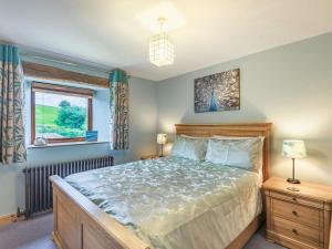 a bedroom with a bed and a window at Peacock Cottage in Dove Holes