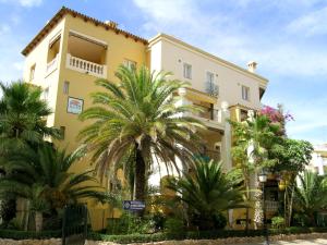 a yellow building with palm trees in front of it at Ona Aldea del Mar in Torrevieja