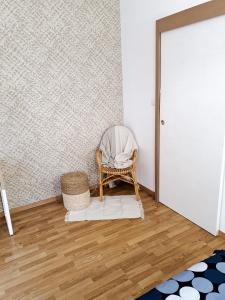 a wicker chair sitting in a room next to a door at Appartement cosy entier, parking gratuit dans la rue in Dijon