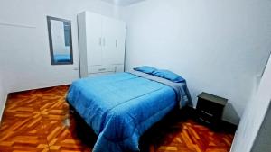 a bedroom with a bed with a blue blanket at Departamento en Pacasmayo in Pacasmayo