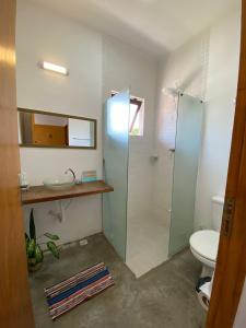 uma casa de banho com um chuveiro, um lavatório e um WC. em Casa Praiana no Guarujá