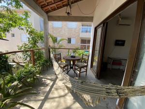 uma rede de descanso numa varanda com uma mesa e cadeiras em Casa Praiana no Guarujá