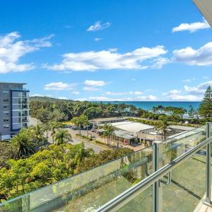 a balcony with a view of a street and the ocean at Tradewinds Apartments in Coffs Harbour