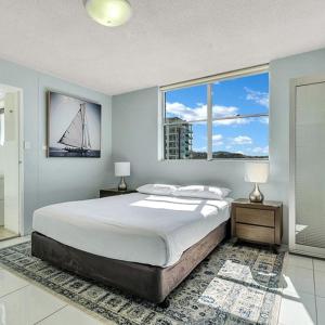 a bedroom with a large bed and two windows at Tradewinds Apartments in Coffs Harbour +156 photos