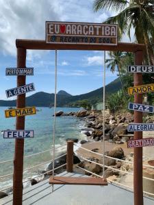 a swing on a beach with street signs at Recanto do Sol in Praia de Araçatiba