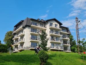 a building on a hill with people in front of it at Villa Mountain View Apartamenty in Szklarska Poręba