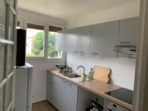 uma cozinha com armários brancos e um lavatório em Superbe T3 spacieux, lumineux et sans vis-à-vis em Vigneux-sur-Seine