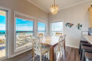 une salle à manger avec une table et des chaises et l'océan dans l'établissement Sandstone, à Île Saint Georges