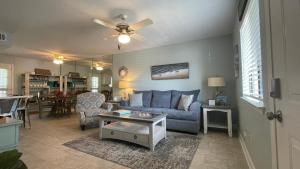a living room with a blue couch and a table at Sunny Daze, Desirable Kid Friendly Resort, 3 minute walk to the Beach, Resort Beachside Pool & Restaurant in Panama City Beach