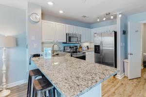 cocina con armarios blancos y encimera de granito en Ocean Mile H-9, en St. George Island