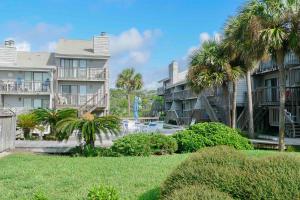 una fila de edificios de apartamentos con palmeras y césped en Ocean Mile H-9, en St. George Island