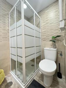 uma casa de banho com um WC e uma cabina de duche em vidro. em Ile Atocha Exterior Olivar em Madri