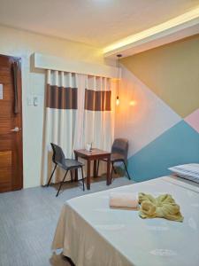 um quarto de hotel com uma cama, uma mesa e cadeiras em NINIE'S PLACE em Puerto Princesa