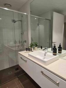 a white bathroom with a sink and a shower at Lux 3 Bedroom Apartment in Southbank in Melbourne