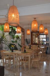 un restaurante con mesas y sillas de madera y luces colgantes en Hotel Primavera Santa Fe, en Santa Fe de Antioquia