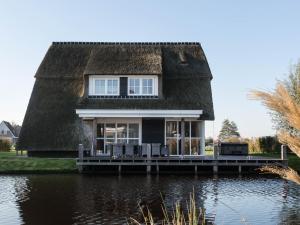 une maison au toit de chaume sur l'eau dans l'établissement Beautiful villa with jacuzzi in a luxury holiday park on the Tjeukemeer, à Delfstrahuizen